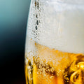 Close-up of a glass of beer with foam and condensation on a blurred background