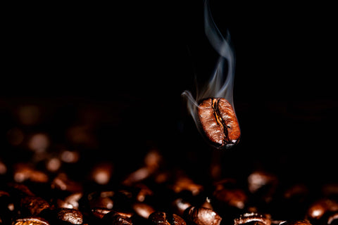 Roasted coffee bean with smoke against a dark background