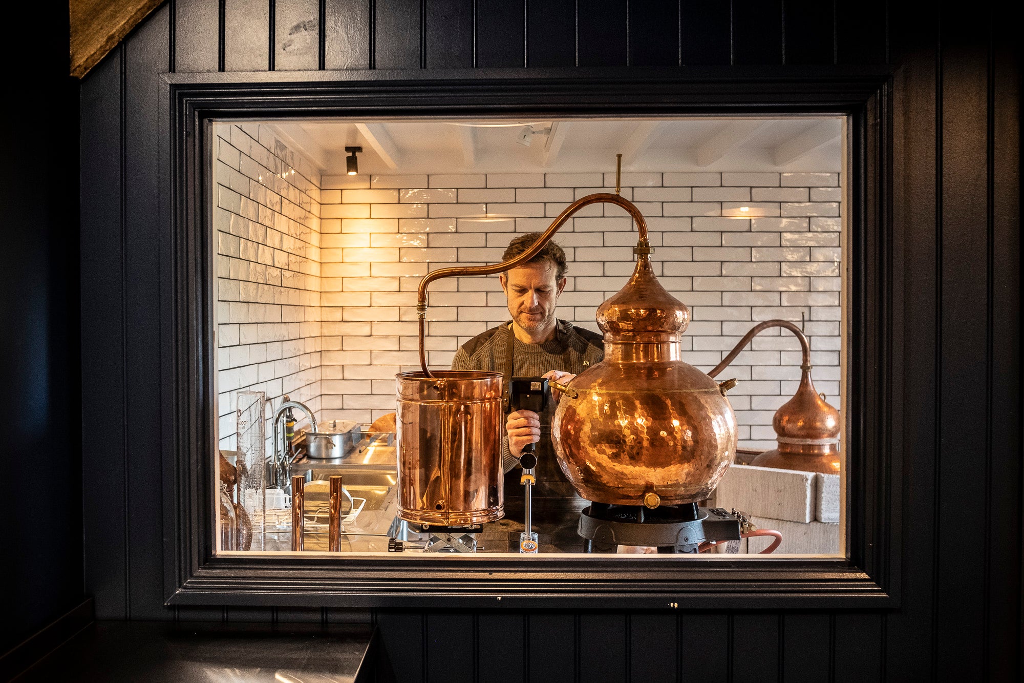 Person working with copper stills in a distillery setting, Spirits. Wiltshire, Downton Distillery