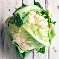 Cauliflower head with green leaves on a wooden surface